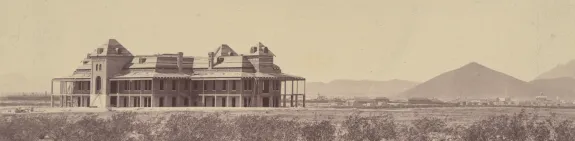 Old Main against a desert backdrop as it's being built, mountains can be seen in the background